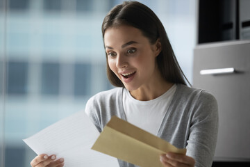 Unbelievable. Excited overjoyed millennial woman corporate worker employee receiving hardcopy of promotion reward notification, happy young female intern getting official letter with hiring decision - obrazy, fototapety, plakaty