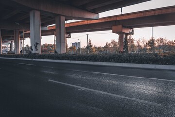 Urban road under overpass bridge at sunset.