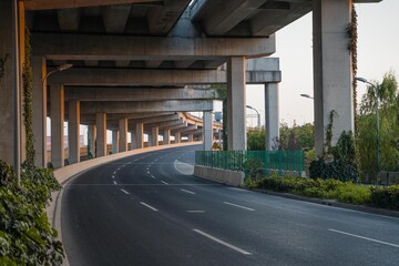 Urban road under overpass bridge at sunset.