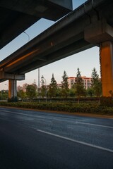 Urban road under overpass bridge at sunset.