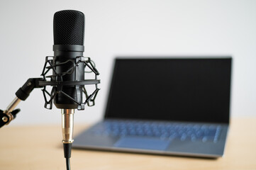 Close-up of a professional microphone on the background of a laptop. Radio broadcaster's desktop