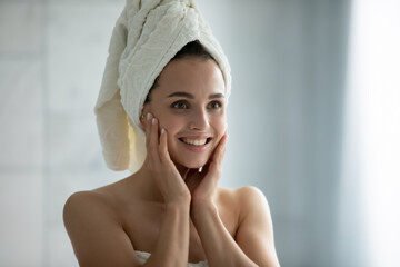 Young and pretty. Beautiful millennial woman looking at bathroom mirror after taking shower, enjoying clean healthy skin white even teeth pretty face bright eyes, pleased satisfied with her reflection