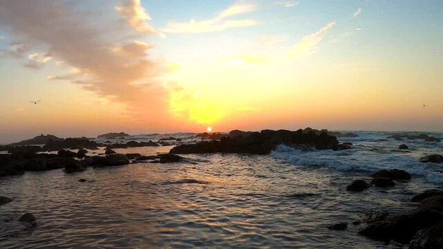 Relaxing nature video of the California sun setting below the horizon on the rocky coastal landscape of Monterey Bay, California. Asilomar State Beach in 4K.