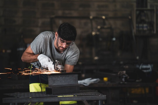 A mechanic wearing safety equipment and operating angle grinder - Metal factory - Industry concept