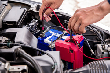 Close up hand of auto mechanic are using measuring equipment tool for checking car battery. Concepts of car fix repair and service maintenance.