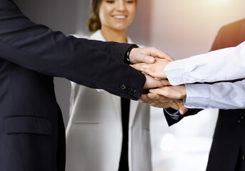 Group of unknown businesspeople are joining hands in a sunny modern office. Unknown businessmen are making circle with their hands. Concept of trust in a business