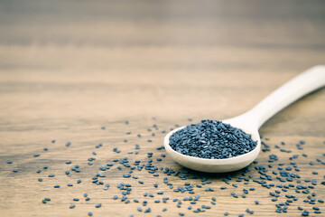 Black sesame seeds in a wooden spoon for healthy food and diet concepts.
