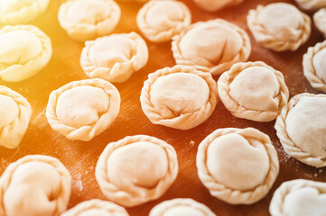 pile of small homemade uncooked dumplings with meat on kitchen table. national traditional Russian cuisine. do it yourself. top view, flat lay