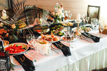 Festive table setting with wine glasses, food and fresh fern