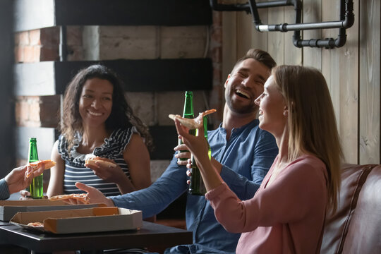 To your health. Happy laughing multiethnic group of young friends colleagues visitors of pub cafe bar spending pleasant weekend together relaxing enjoying beer and pizza glad meeting in favorite place - Powered by Adobe