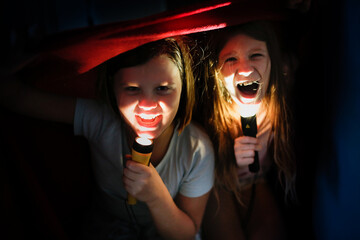 Crazy kids under a blanket with flashlights, scary stories and horror stories, kids scare for Halloween.