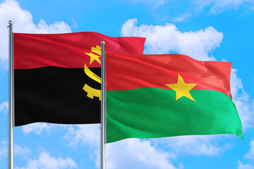 Burkina Faso and Angola national flag waving in the windy deep blue sky. Diplomacy and international relations concept.