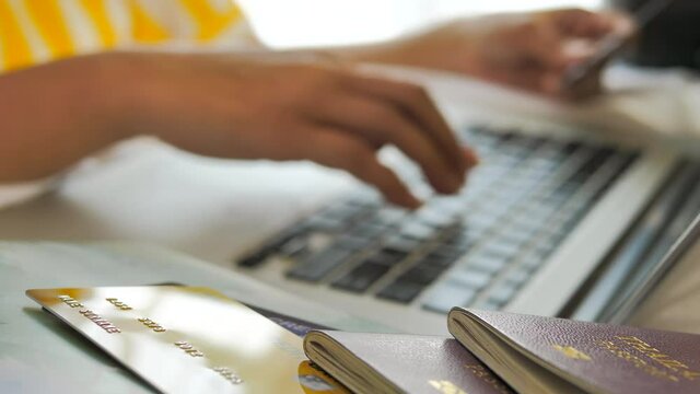 Woman booking air plane tickets online on laptop and holding credit card. Happy women preparing for vacation travel trip using computer buying doing internet payment at home