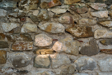 Stone wall, old crumbling stone wall made of stone and sandstone, abstract nature background. Texture of old stone masonry