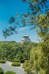 Beautiful osaka castle surrounded by trees under a blue sky in the afternoon