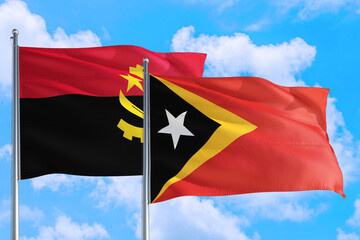 East Timor and Angola national flag waving in the windy deep blue sky. Diplomacy and international...