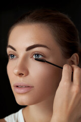 Fototapeta premium .Eyebrow makeup. Beautiful woman shaping brows with eyebrow brush closeup. Beauty girl model with professional makeup contouring eyebrows