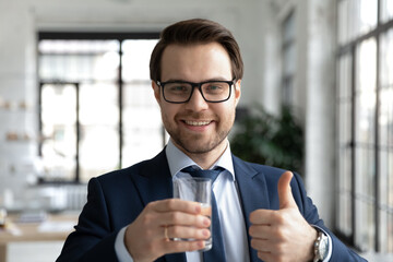 Headshot portrait of happy healthy young businessman employee in eyeglasses and formal wear holding...