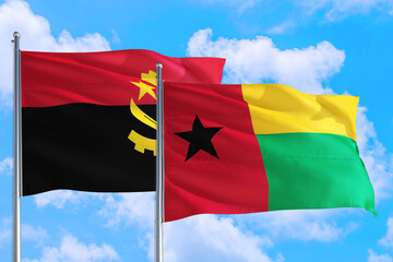 Guinea and Angola national flag waving in the windy deep blue sky. Diplomacy and international relations concept.