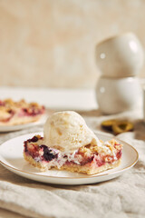 Delicious plum cake with crumble and ice cream on a white table