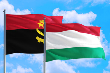 Hungary and Angola national flag waving in the windy deep blue sky. Diplomacy and international relations concept.