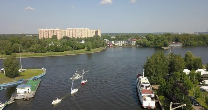 4K high quality calm windless bright summer morning aerial video of Moscow Channel yacht club embankment, green trees, wooden pier and shore with moored anchored boats and yachts near Moscow, Russia
