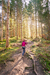 Fototapeta premium Hiking in the forest, autumn time. Girl in sportswear, sunbeams and warm color
