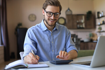 Happy young business man is analizing financial documents from home during self isolation.