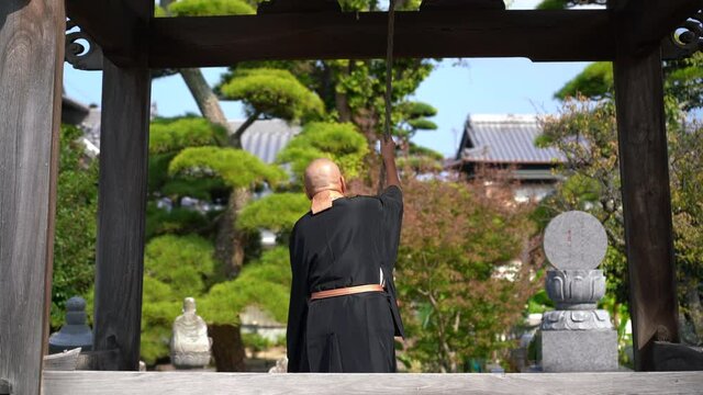 お坊さんが鐘を鳴らしているイメージ