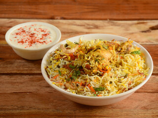 Traditional Hyderabadi Chicken dum Biryani made of Basmati rice cooked with masala spices, served with yogurt, selective focus