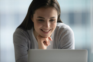 Great. Happy smiling young woman reading good news from pc screen at workplace in office feeling...