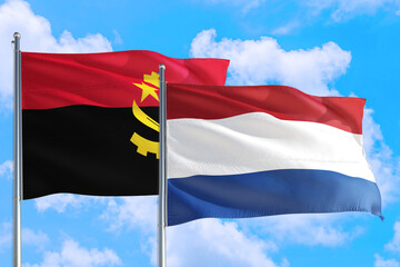 Netherlands and Angola national flag waving in the windy deep blue sky. Diplomacy and international relations concept.