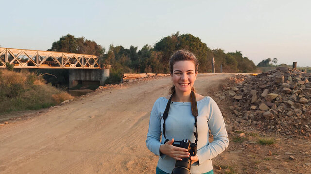 Smiling woman holding photo camera on dirt road in interior of Brazil