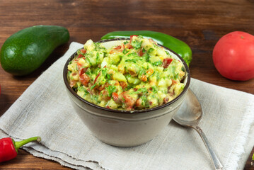 Homemade guacamole - traditional Mexican appetizer with avocado, onion and tomato in a bowl