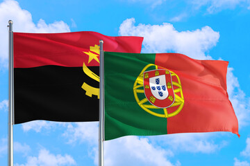 Portugal and Angola national flag waving in the windy deep blue sky. Diplomacy and international...