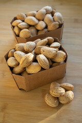 Almonds on table in hard shells, group of dry ripened fruits in cardboard boxes, crop food ingredients ready for cooking
