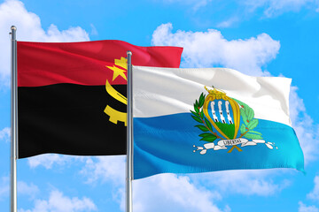 San Marino and Angola national flag waving in the windy deep blue sky. Diplomacy and international relations concept.
