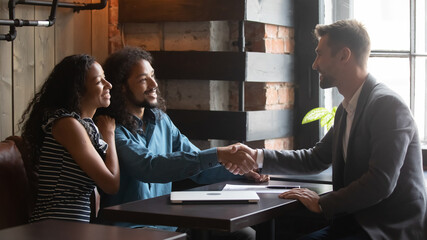 Good deal. Happy millennial spouses customers clients shaking hand of insurance agent lawyer...
