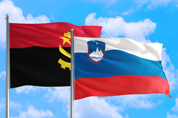Slovenia and Angola national flag waving in the windy deep blue sky. Diplomacy and international relations concept.