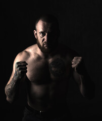 Studio session with one muscular man in low-key light conditions