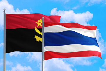 Thailand and Angola national flag waving in the windy deep blue sky. Diplomacy and international relations concept.