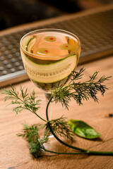 Close-up view of glass with drink and slice of cucumber standing on wooden surface of bar