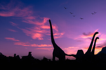 Fototapeta premium silhouette dinosaur in the park and pink color sky backgrounds