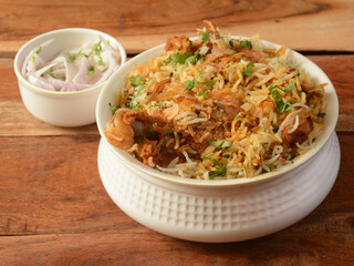 Traditional Hyderabadi Chicken dum Biryani made of Basmati rice cooked with masala spices, served with Onion raita, selective focus