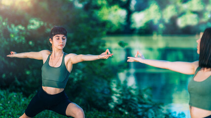 Fototapeta na wymiar Yoga Women by The Lake. Warrior Pose