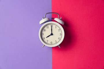 Retro alarm clock on red and purple table background, vintage lifestyle concept