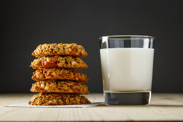 Sweet oatmeal cookies with a glass of milk on a wooden table.