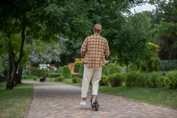 Fototapeta premium Man in white pants riding a push scooter