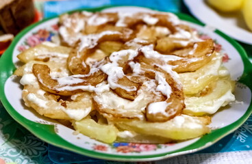 Slices of fried zucchini with sour cream in a colored plate close-up