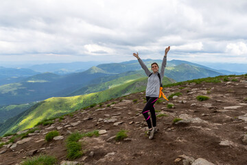 Sporty, happy girl with raised arms on the top of the mountain. Tourism.